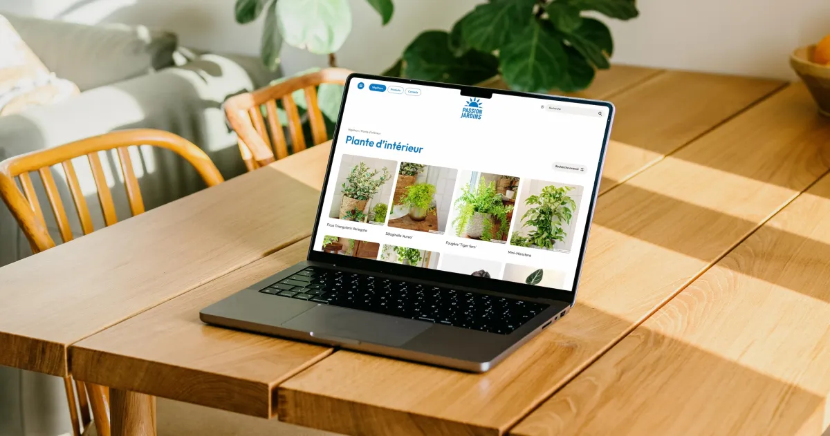Ordinateur portable affichant une page intitulée « Plante d’intérieur », avec des photos de plantes, sur une table en bois entourée de verdure.